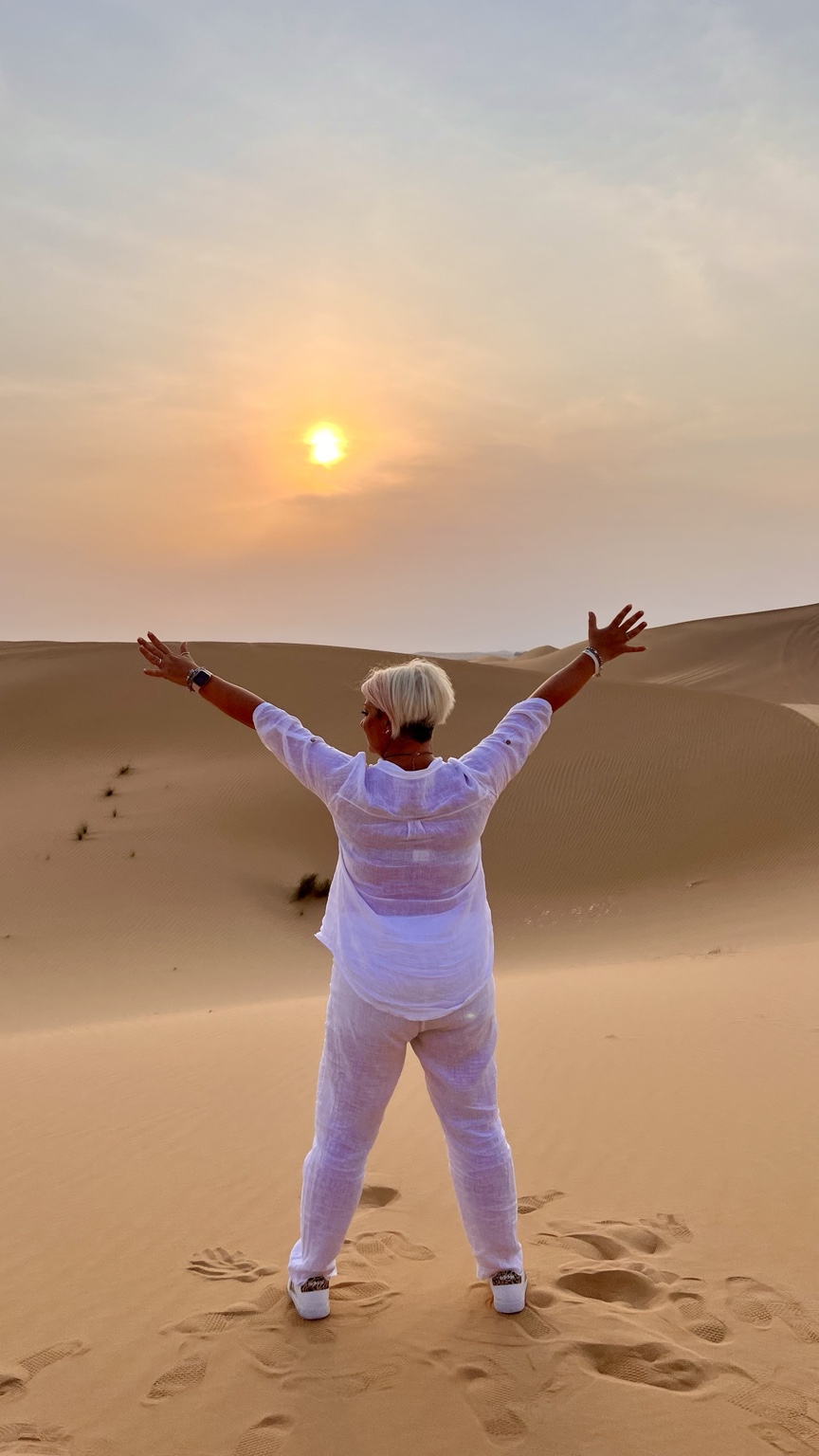 Patrizia tra le dune al tramonto, con le braccia aperte